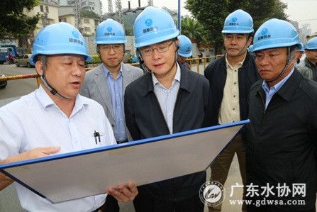 韶关水司经理甘志高(左一)向蓝佛安书记(中)介绍工程建设情况